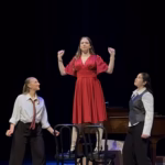 Sarah Genne as Linda Lee Thomas in the Musical Theatre Composer's Showcase: Cole Porter at Interlochen Arts Academy, standing on chairs in a red dress with two cast members looking up at her.
